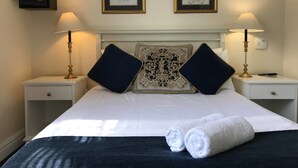 A hotel room with a large bed, two nightstands, two lamps, two framed pictures, and a decorative headboard. - Altona Guest House (Cape Town)