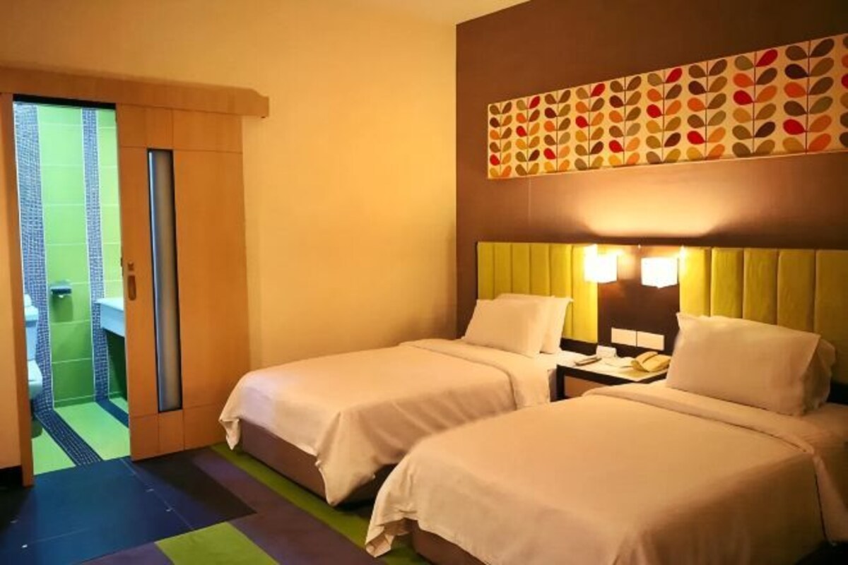 Une chambre d’hôtel avec deux lits, une salle de bain avec douche et une porte donnant sur un balcon.