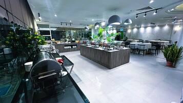 A modern restaurant with a central island, glass tables, and potted plants.
