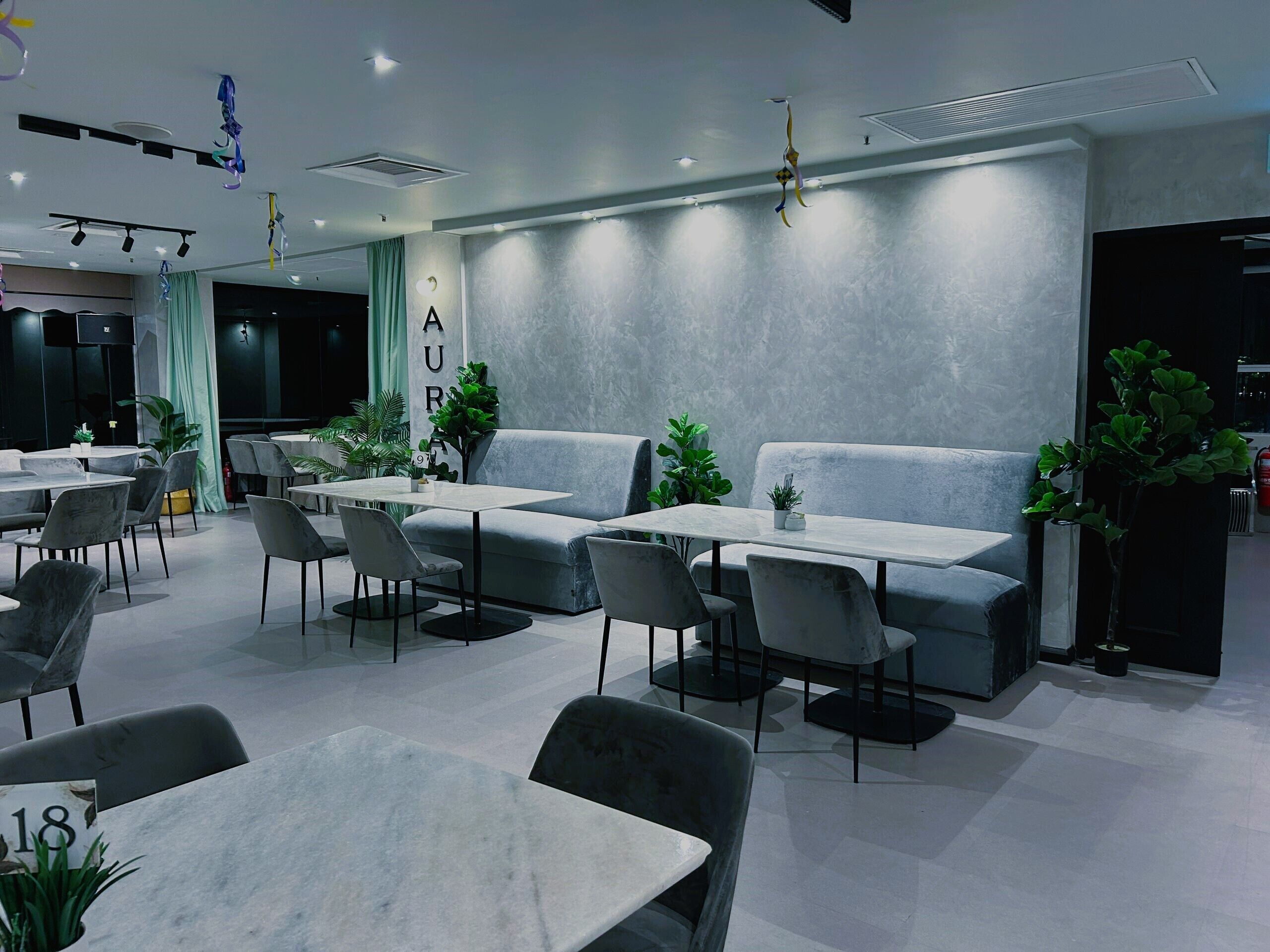 A modern dining area with tables and chairs, a sofa, and potted plants.