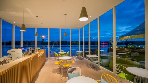 En moderne bar med udsigt over vandet og byens skyline i skumringen.