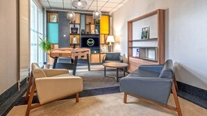 Eine moderne Lobby mit Sitzgelegenheiten, einem Fernseher und einer Rezeption.