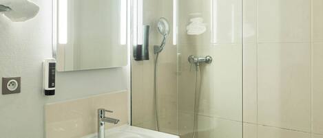 Uma casa de banho moderna com lavatório, espelho e cabine de duche em vidro.