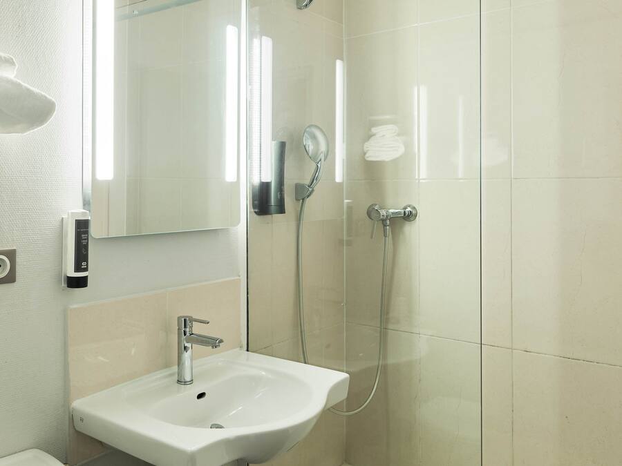 A modern bathroom with a sink, mirror, and glass-enclosed shower.