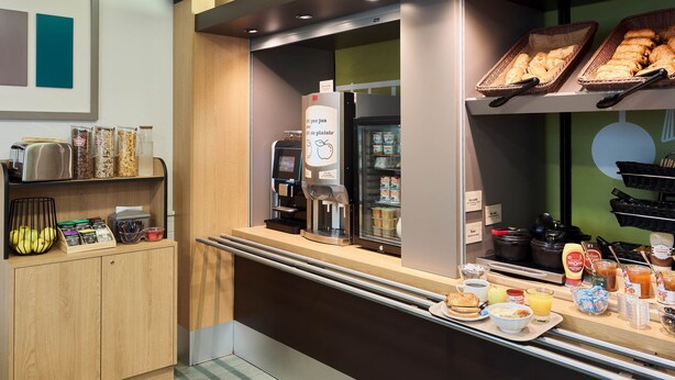 Una barra de desayuno con cafetera, refrigerador y diferentes alimentos.