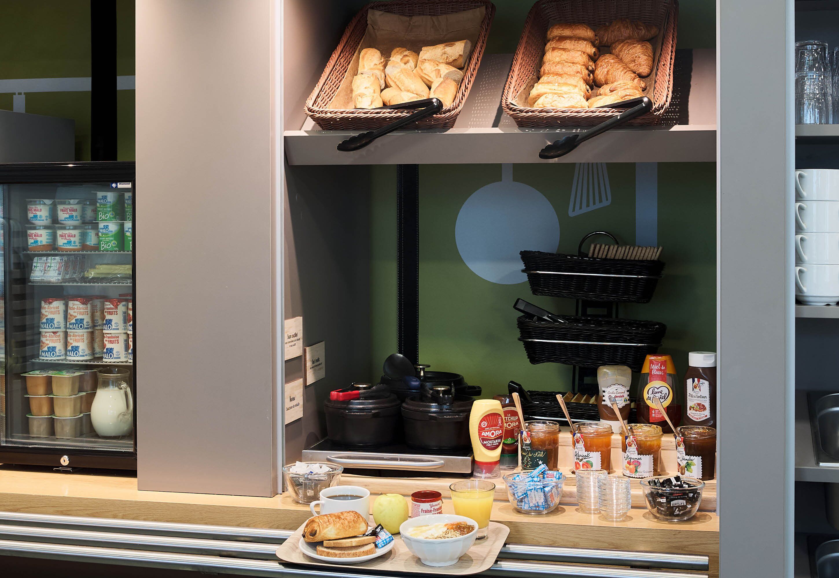 Een ontbijttafel met brood, gebak, toevoegingen en drankjes.