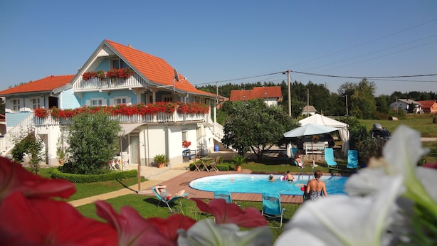 Une maison avec un toit rouge, une piscine et un jardin.