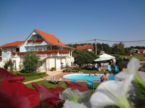 Ein Haus mit rotem Dach, Swimmingpool und Garten.