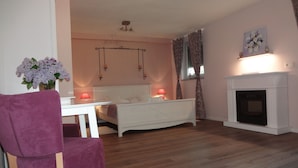 Une chambre à coucher avec un lit, une chaise, une table, une cheminée et un vase de fleurs.