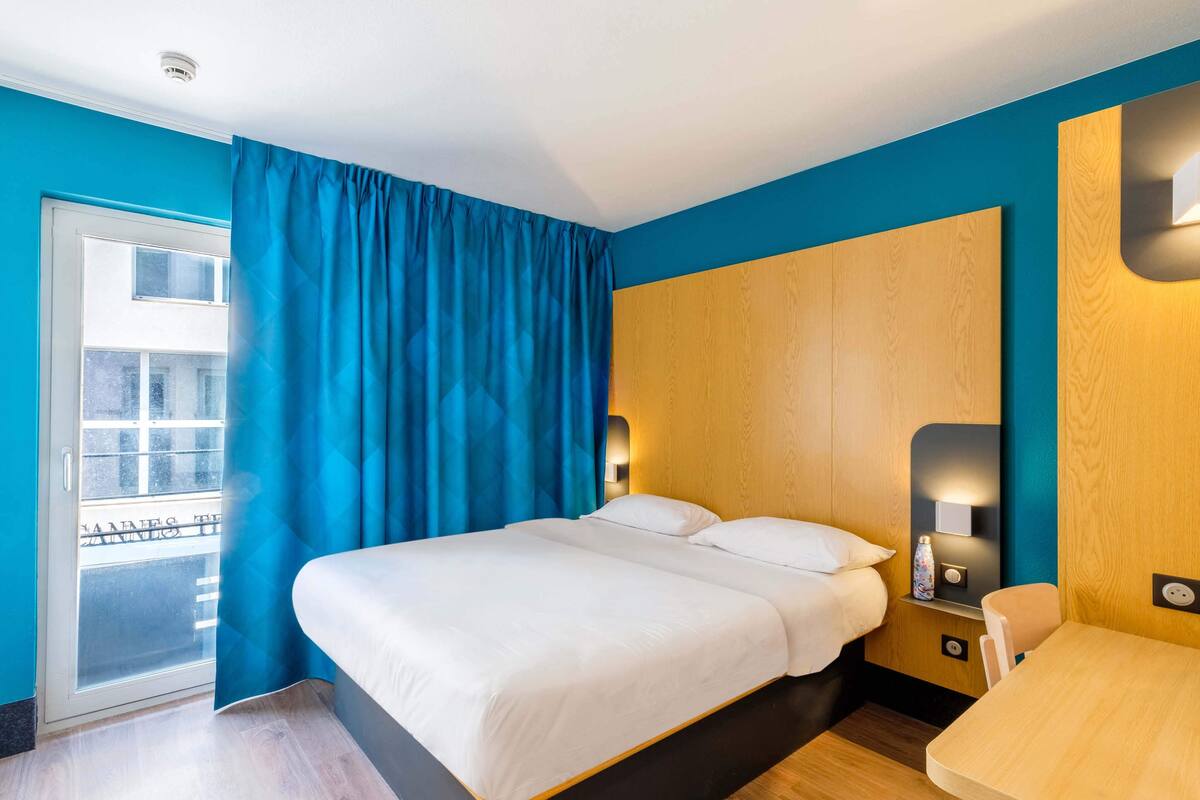 Una habitación de hotel con una cama, un escritorio y vistas al exterior.