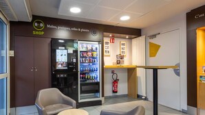 A hotel lobby with a shop, vending machines, seating area, and a fire extinguisher. - B&B HOTEL CHARTRES Le Forum (1) (Le Coudray)