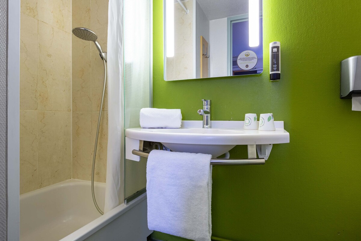 Une salle de bain avec une baignoire, un lavabo avec une serviette et un miroir.
