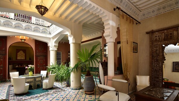 Un interior tradicional con suelo estampado, disposición de asientos y columnas decorativas.
