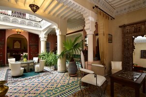 Un interior tradicional con suelo estampado, disposición de asientos y columnas decorativas.