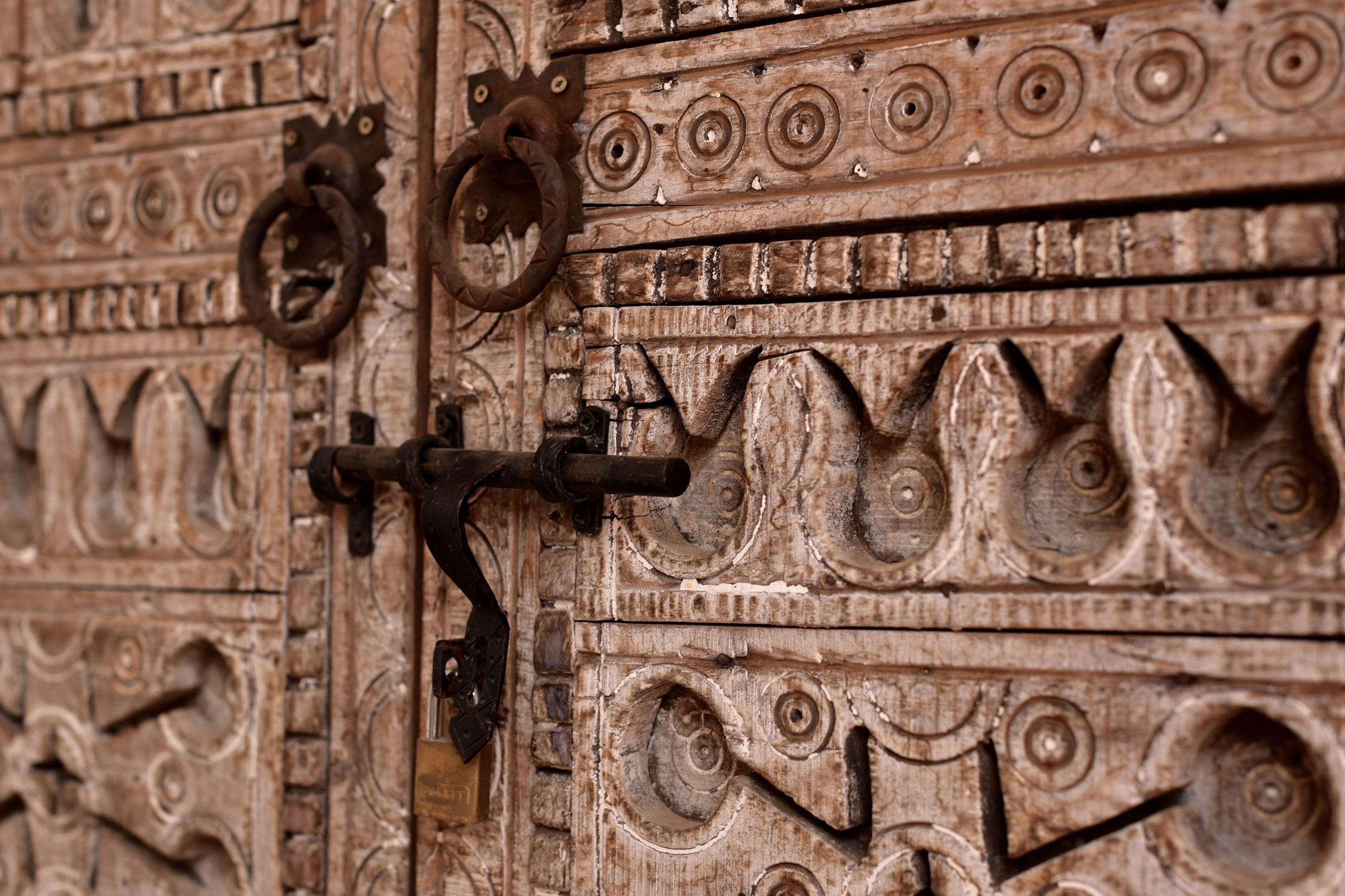 A wooden door with intricate carvings and a metal latch.