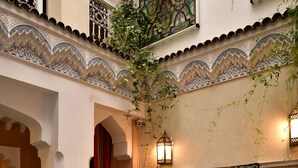 Un patio interior con un conjunto de sofás, un muro decorativo y una planta colgante.