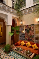 Un patio interior con un conjunto de sofás, un muro decorativo y una planta colgante.
