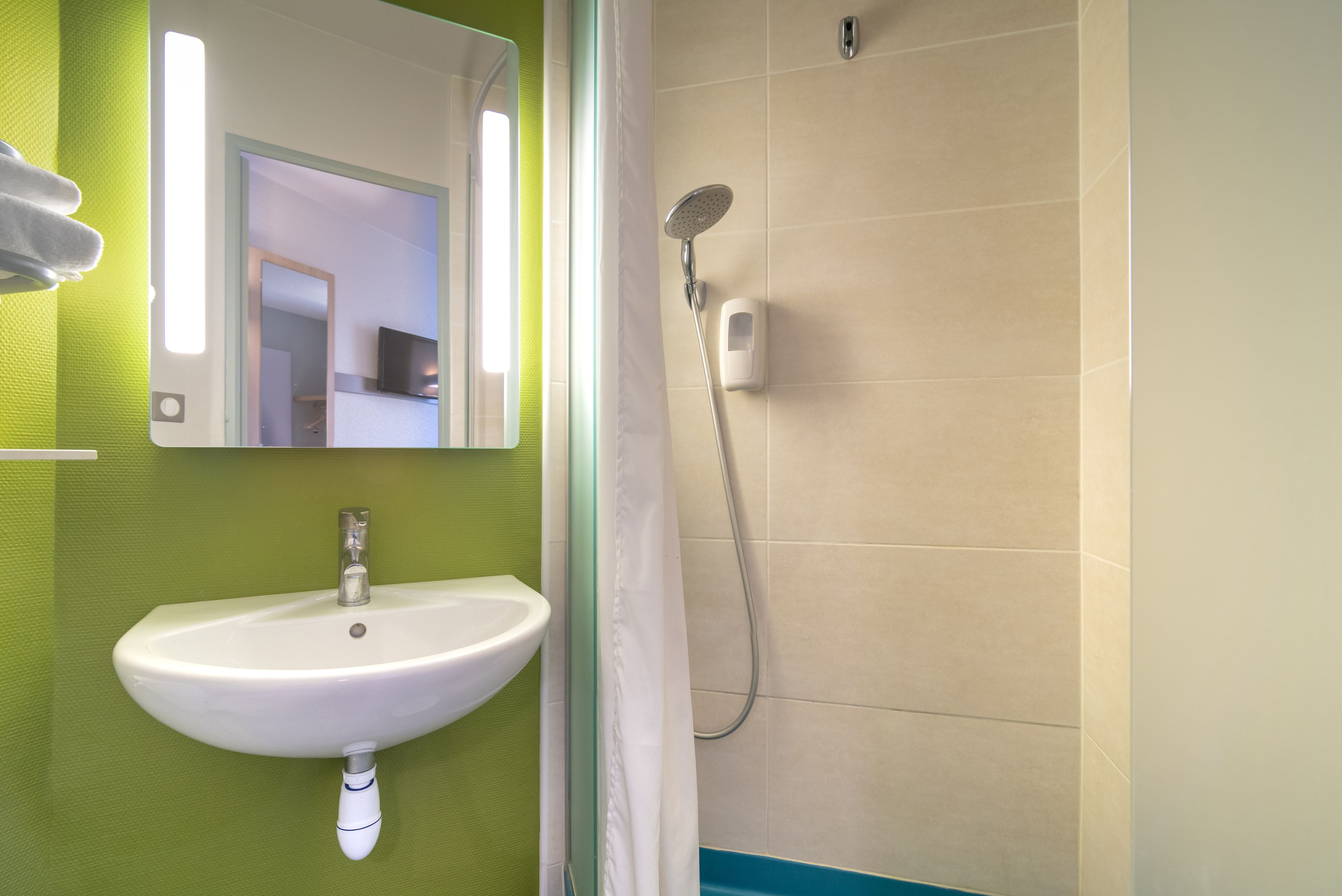 A bathroom with a white sink, a mirror, and a shower.