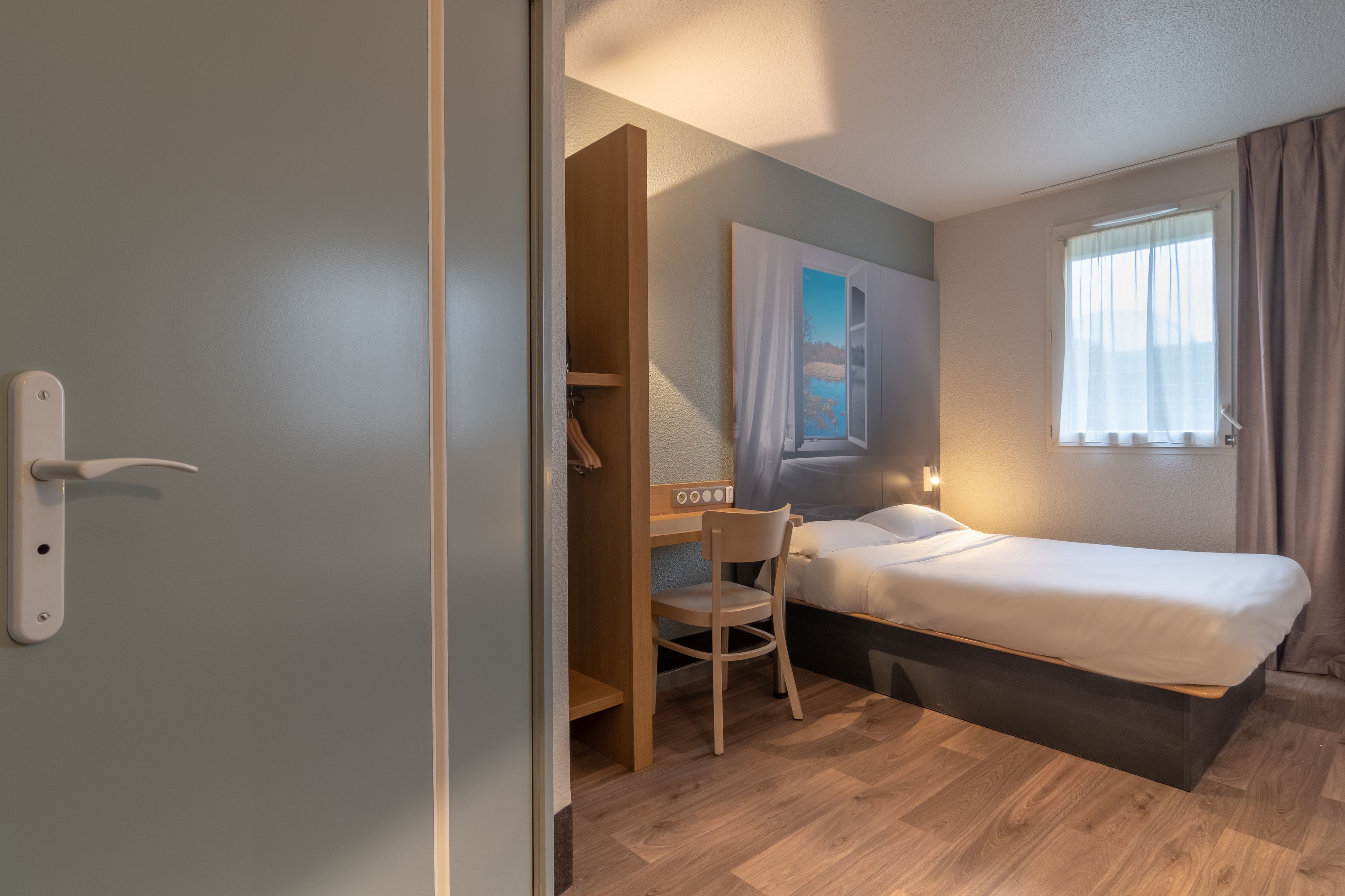A compact room with a single bed, a desk, and a chair.