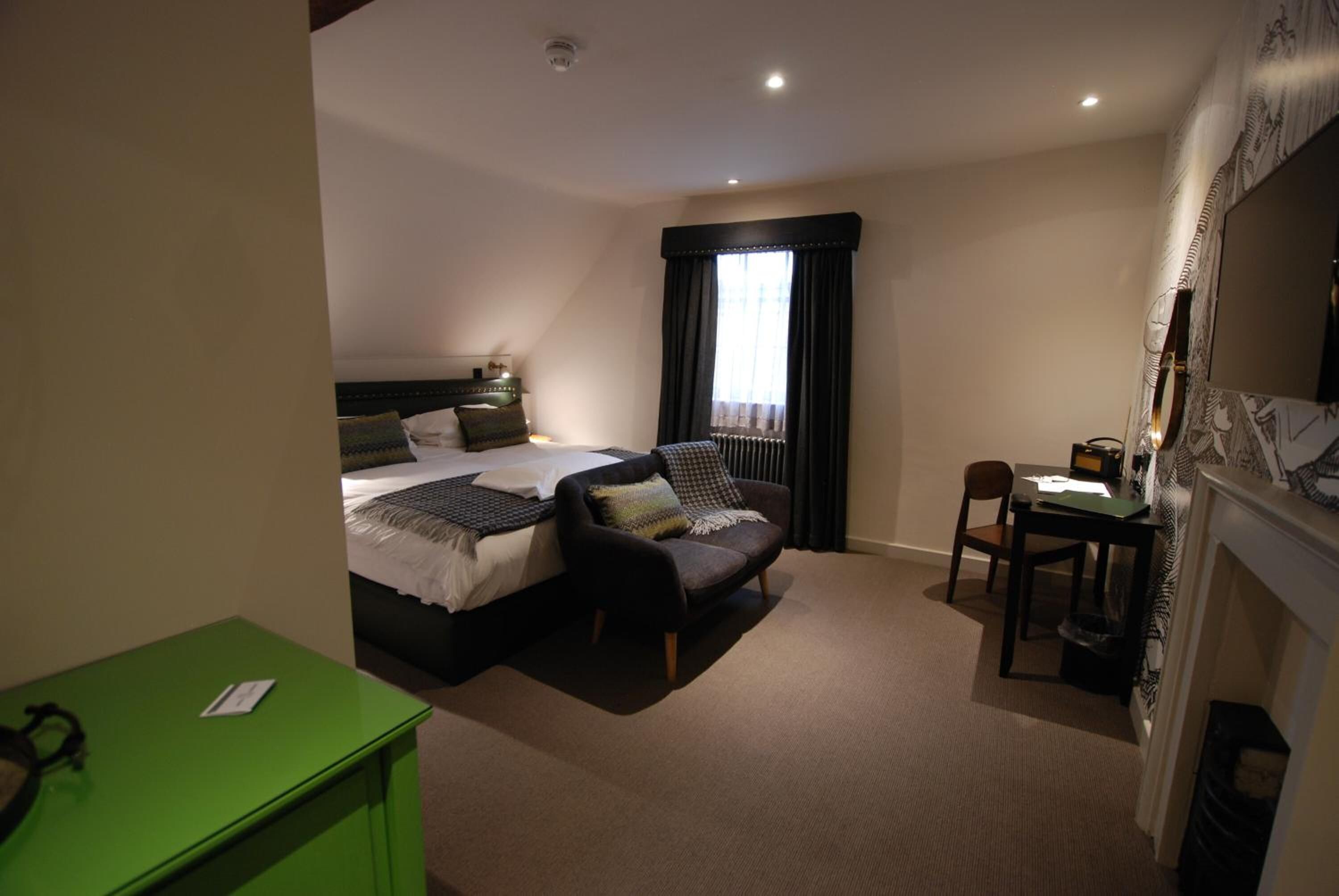 Quarto de hotel com uma cama, um sofá, uma escrivaninha e um armário verde.