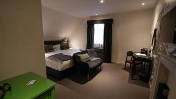 Quarto de hotel com uma cama, um sofá, uma escrivaninha e um armário verde.