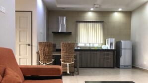 A compact living space with a sofa, a dining area with chairs, a kitchen with a refrigerator, and a window with blinds. - Fuuka Villa (Langkawi)
