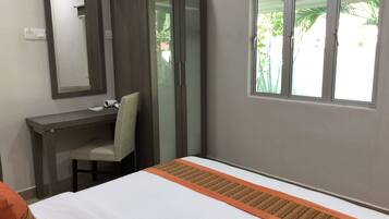 A hotel room with a bed, a desk, a chair, a wardrobe, and a window with a view of greenery.