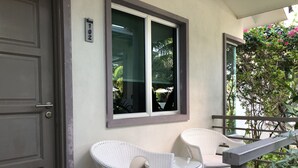A room with two white wicker chairs, a window with a view of greenery, and a door with a number plate. - Fuuka Villa (Langkawi)