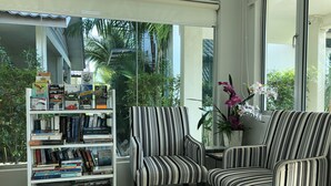 A modern living room with a striped armchair and a bookshelf filled with books and magazines. - Fuuka Villa (Langkawi)