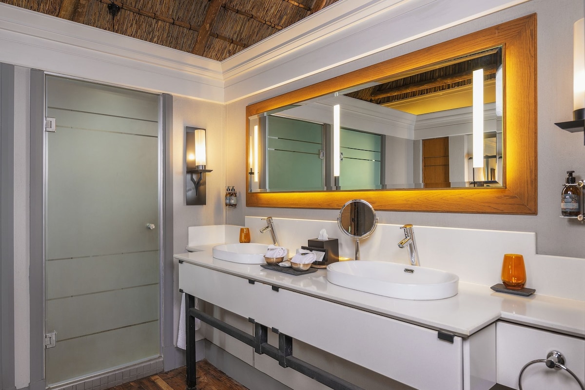 A modern bathroom with two sinks, a large mirror, and a glass shower enclosure.