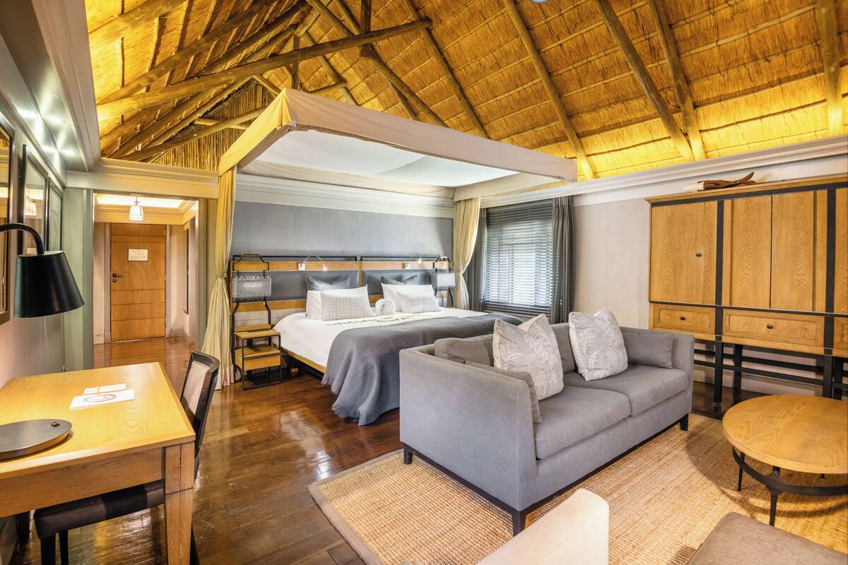 A room with a bed, a sofa, a dining table, and a wooden cabinet.