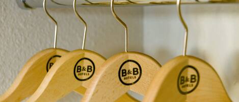 Perchas de madera con un logo en una barra de metal.