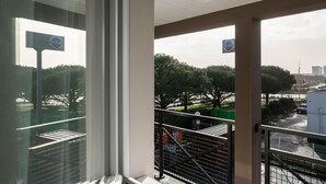 Un balcon donnant sur un parking, des arbres et un panneau sur lequel on peut lire le mot « Vibes ».