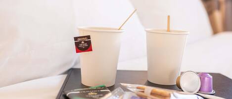 Two disposable cups with straws on a tray, a packet of cigarettes, and a lighter.