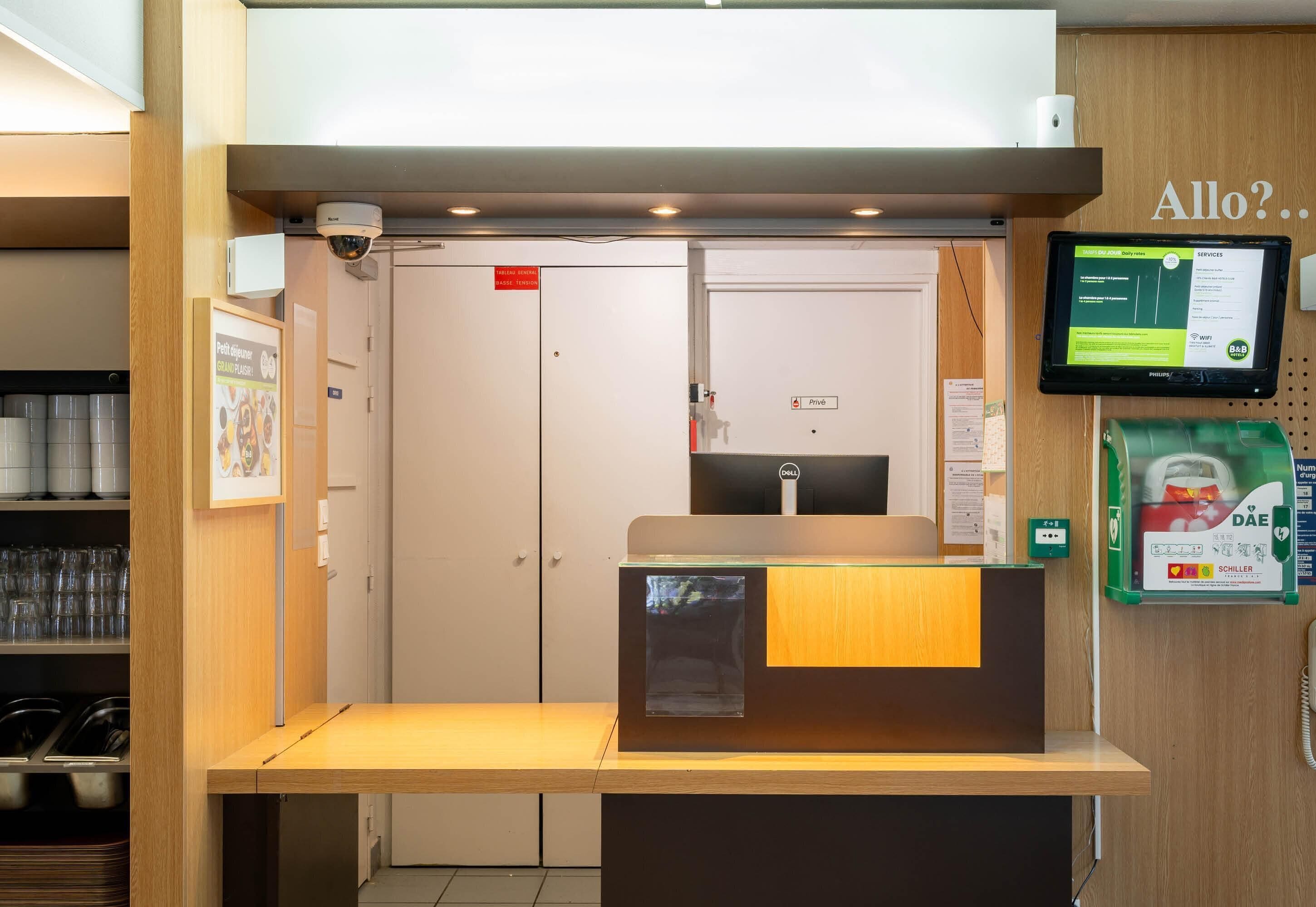A reception desk with a computer monitor, a security camera, and a sign indicating a private area.