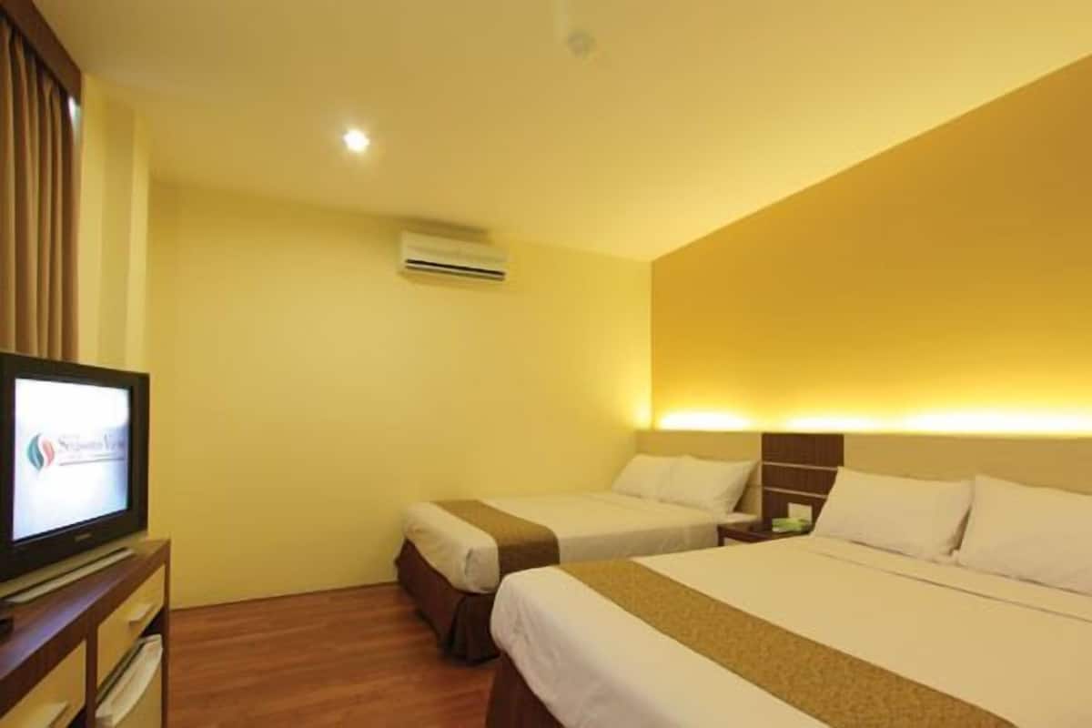 A hotel room with two beds, a TV, and a desk.