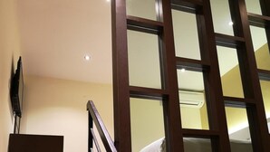 A staircase with dark wooden railings and glass panels, leading to a room with a bed and a ceiling light. - Seasons View Hotel (Kuantan)
