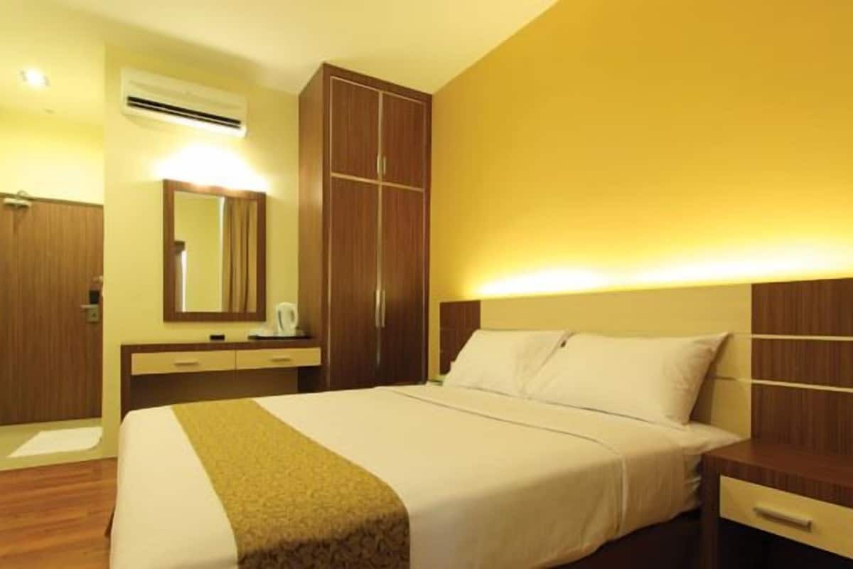 A hotel room with a bed, bedside table, nightstand, wardrobe, and a mirror.