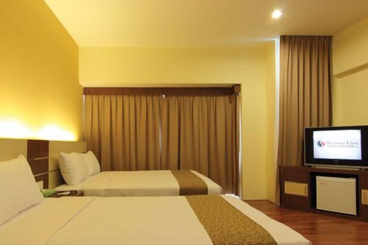 A hotel room with two beds, a television, and a small desk.