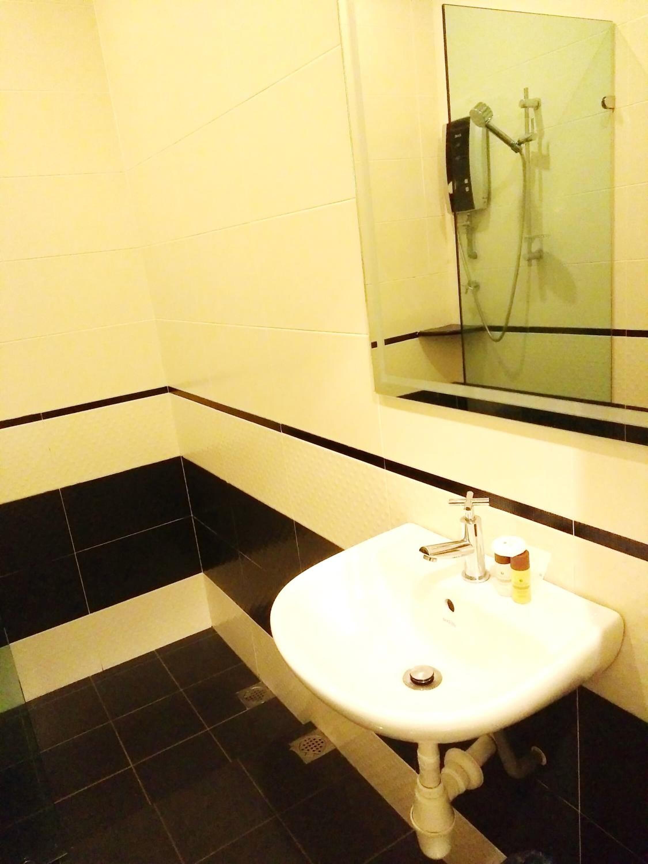 A bathroom with a white sink, black and white tiled walls, and a glass shower enclosure.