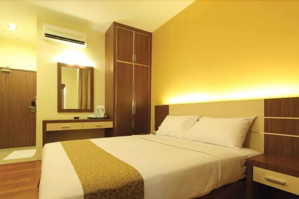Habitación de hotel con cama, mesita de noche, armario y espejo.