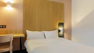 Una habitación de hotel con una cama, un escritorio y una silla.