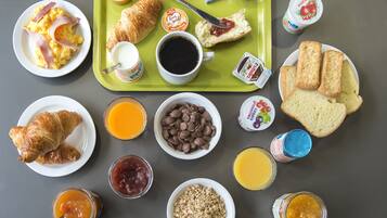 A breakfast tray with croissants, scrambled eggs, and various spreads.