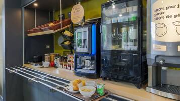 A breakfast bar with a coffee machine, a refrigerator, and a tray with food and drinks.