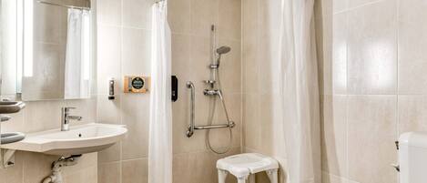 A bathroom with a shower, toilet, sink, and a small step stool.