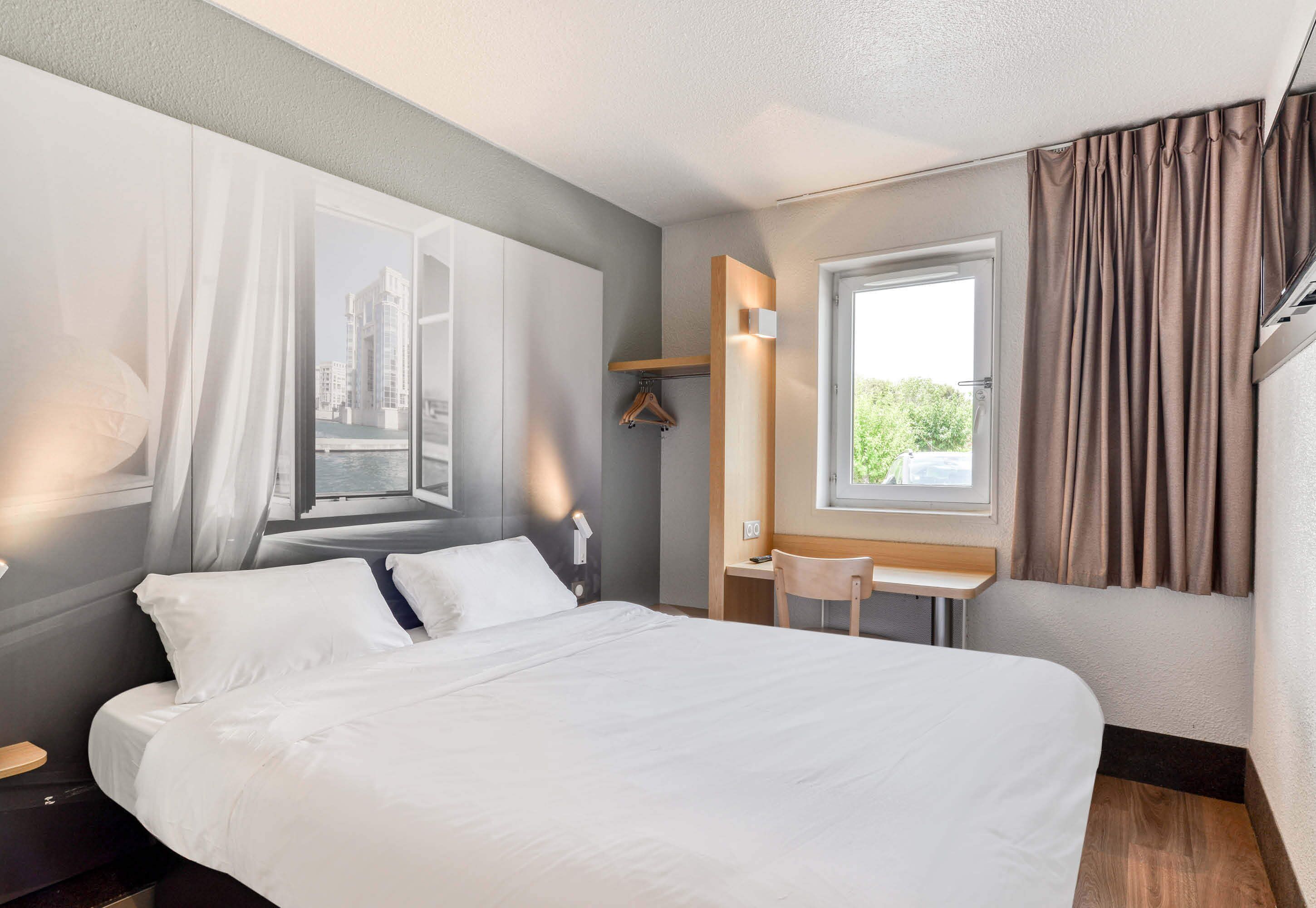 Una habitación de hotel moderna con una cama grande, un escritorio y una ventana con cortinas.