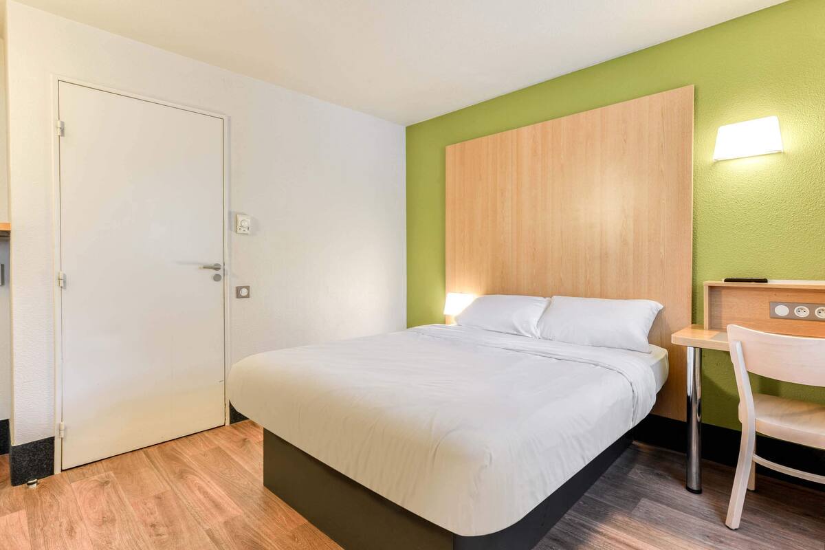 Een hotelkamer met een bed, een bureau en een stoel.