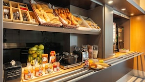 Un ricco buffet per la colazione con pane, dolci, frutta e bevande.