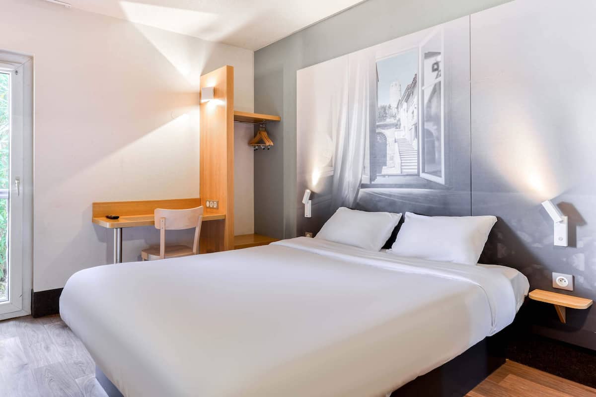 Une chambre d’hôtel moderne avec un grand lit, un bureau et une chaise.