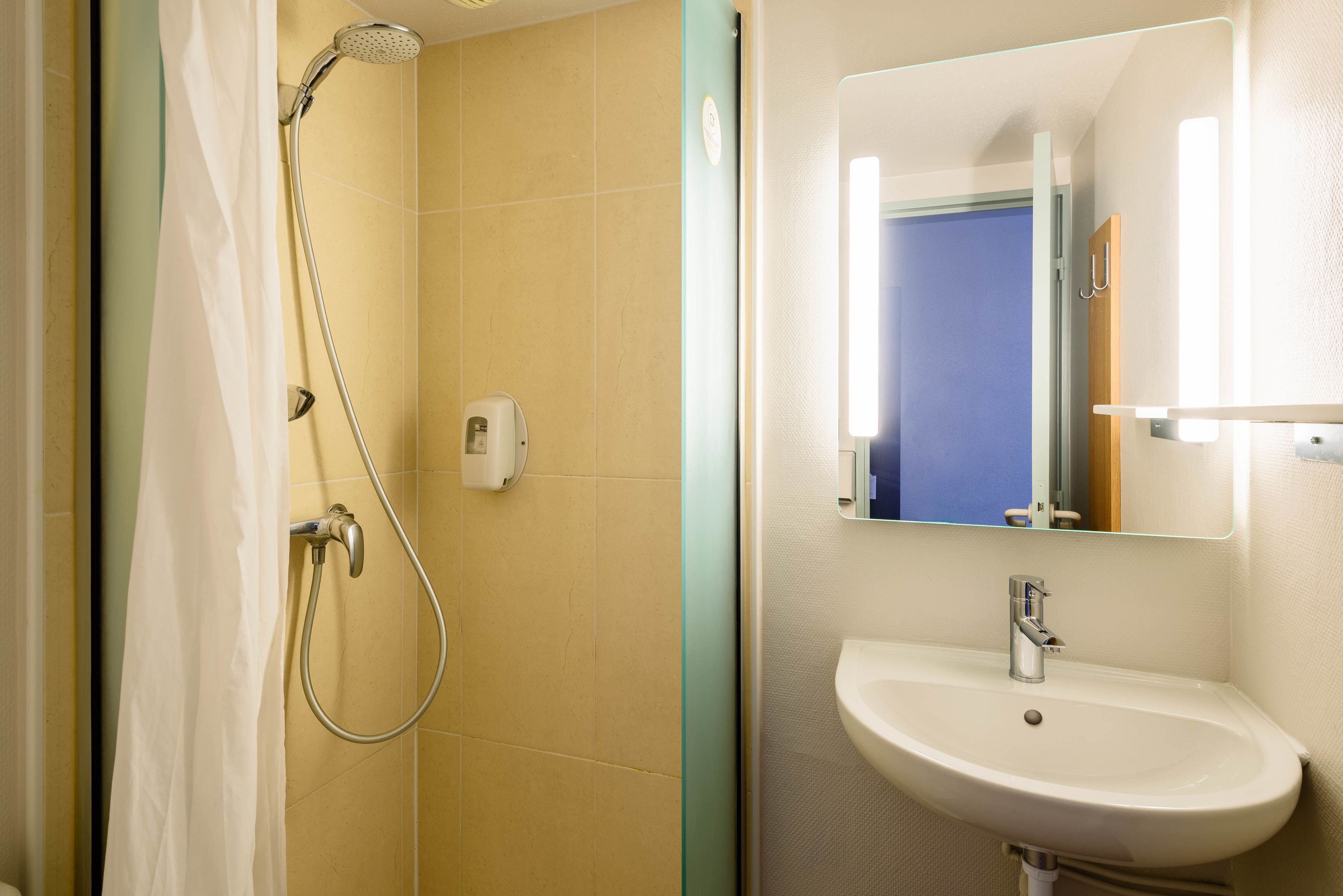 Un baño con ducha, lavabo y espejo.